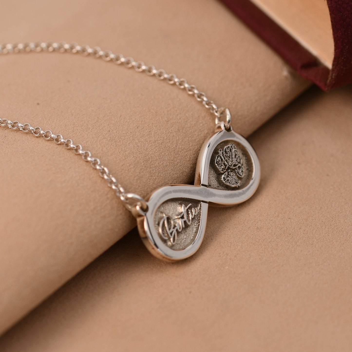 Silver necklace with interlocking heart pendants on a beige surface