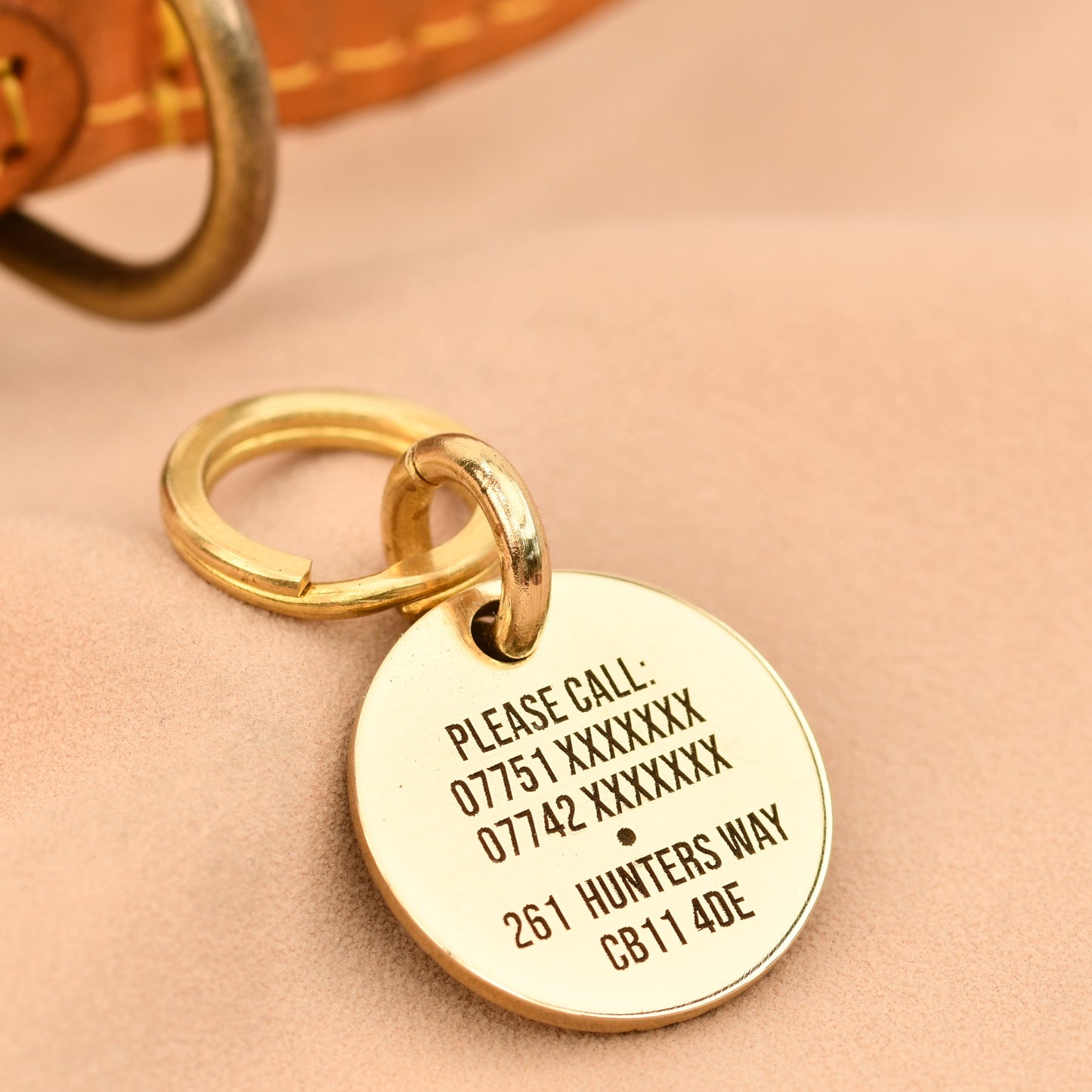 Gold dog tag with engraved information on a beige background