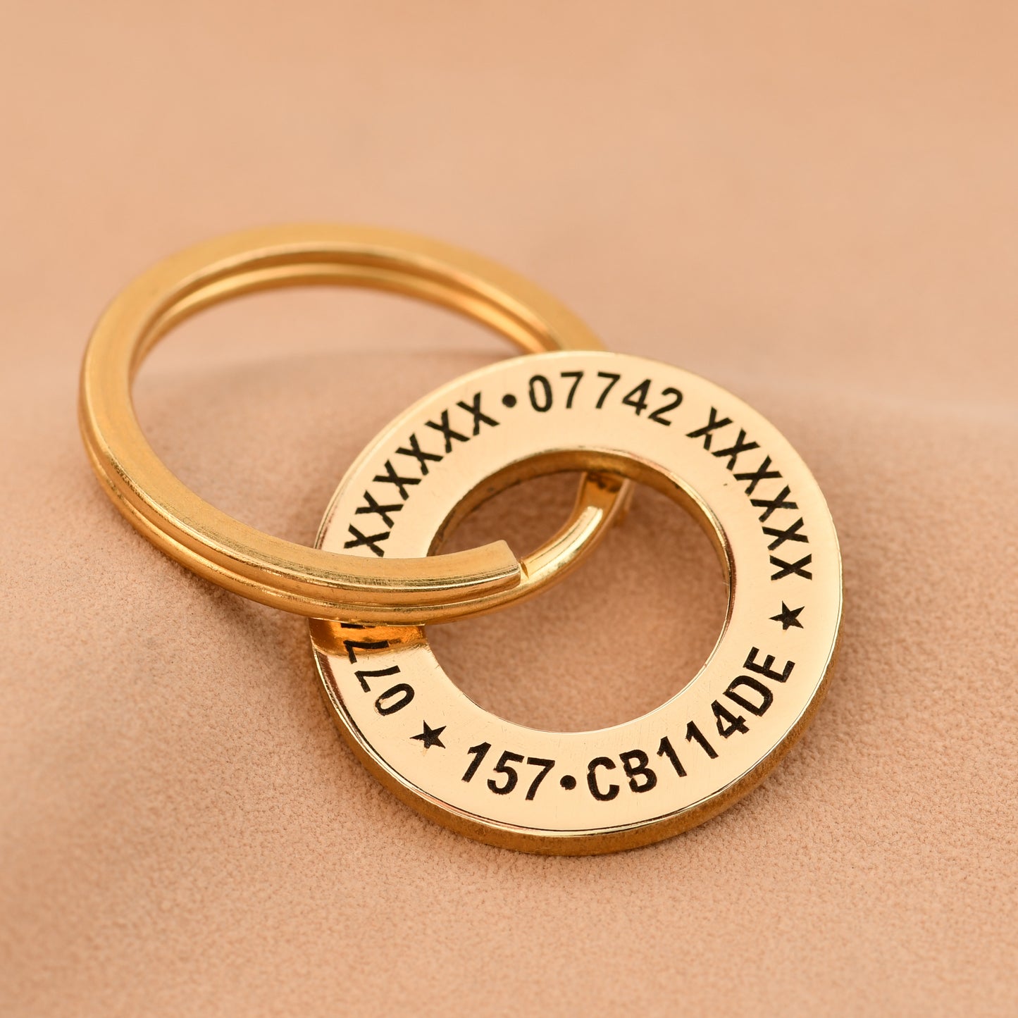 Gold keychain with engraved text on a beige background