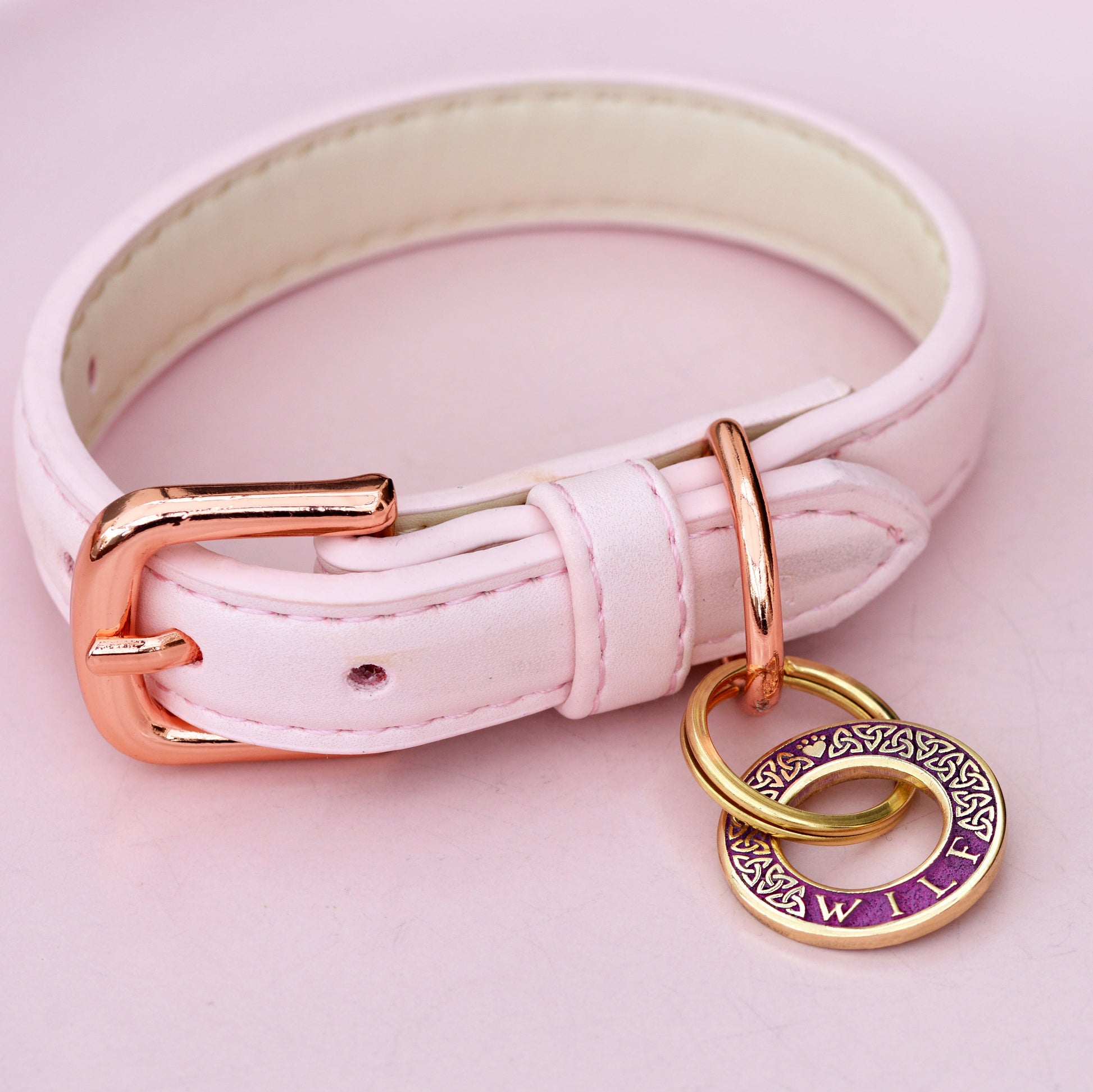 Hoop-shaped brass ID tag with engraved Celtic pattern, handmade in the UK. Suitable for dogs, cats, and horse bridles. Shown attached to a collar for display.