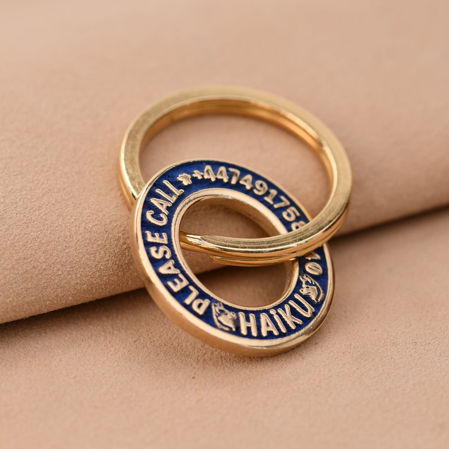 Gold ring with blue engraving on a beige fabric background