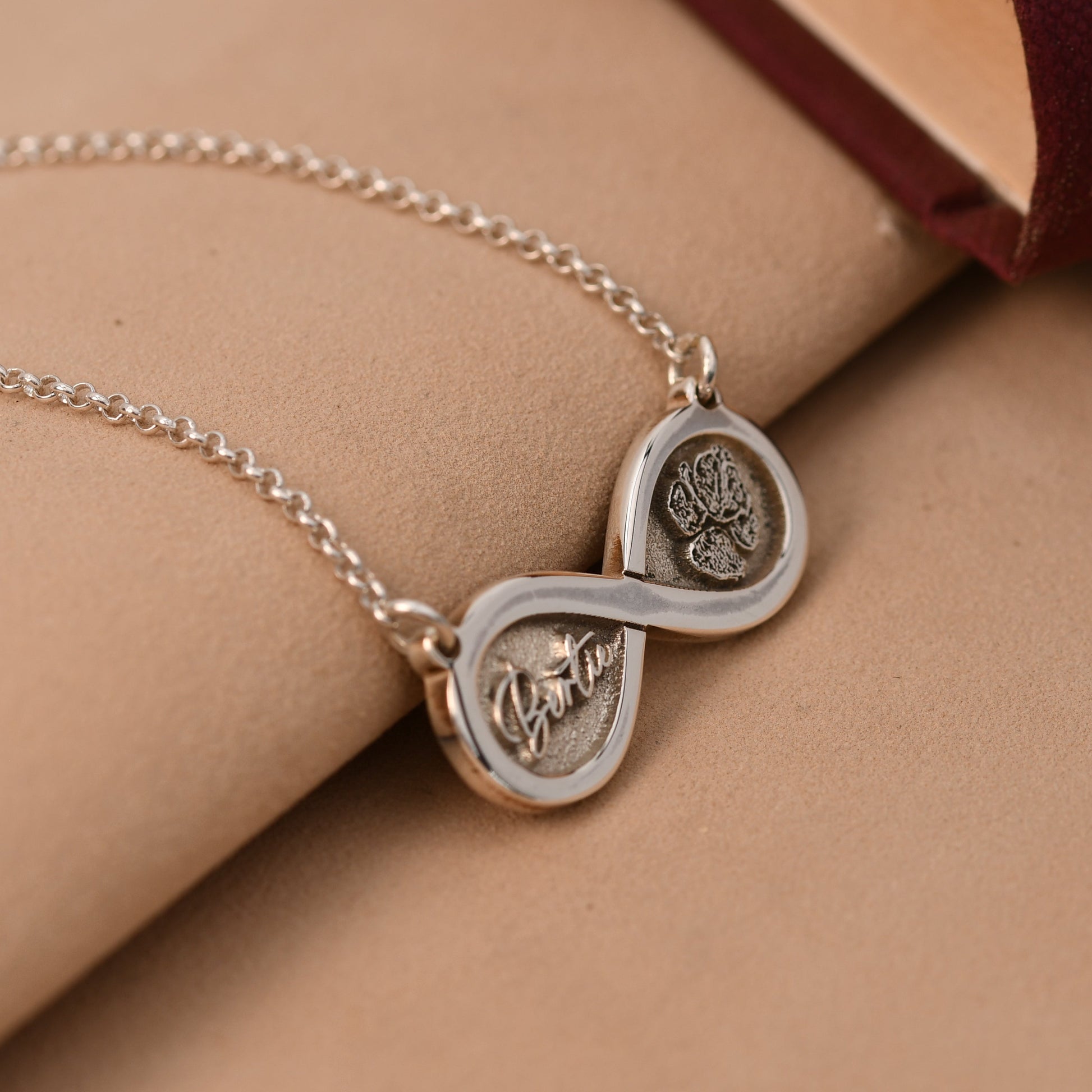 Silver necklace with interlocking heart pendants on a beige surface
