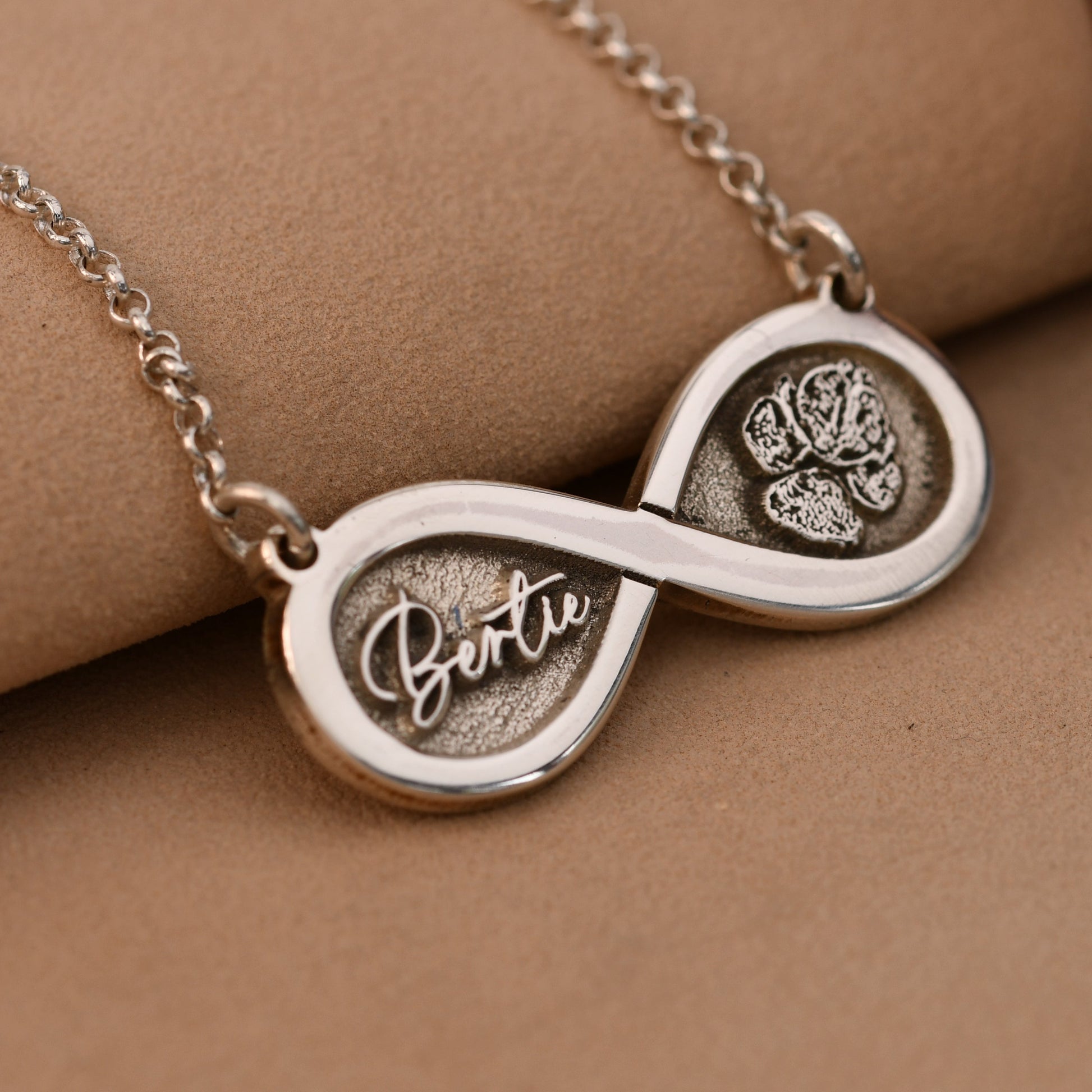 Silver necklace with an infinity symbol pendant on a beige background