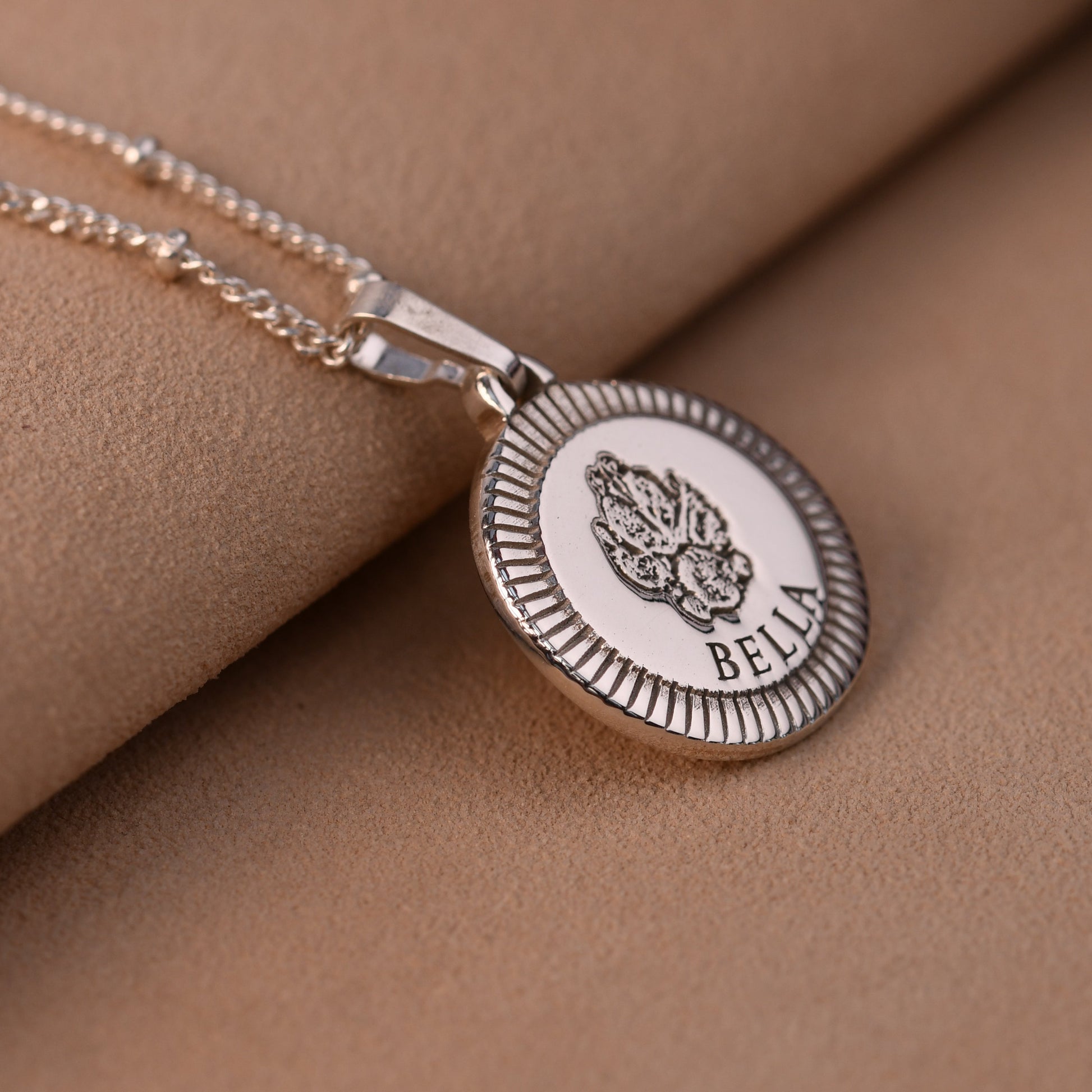 Silver necklace with a round pendant on a beige fabric background