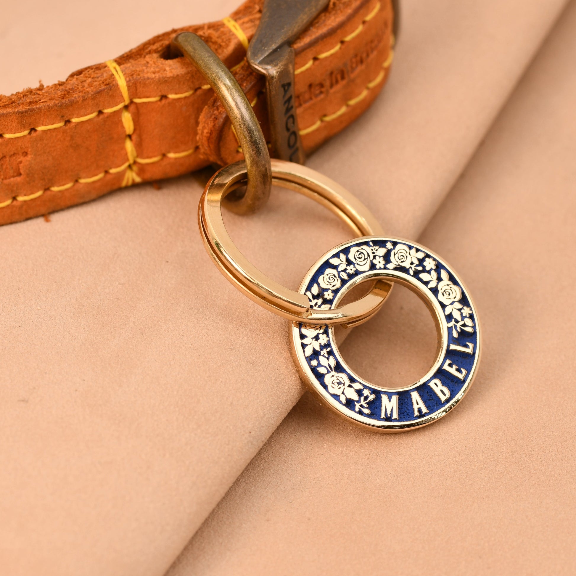 Dog collar with a decorative tag on a beige fabric background