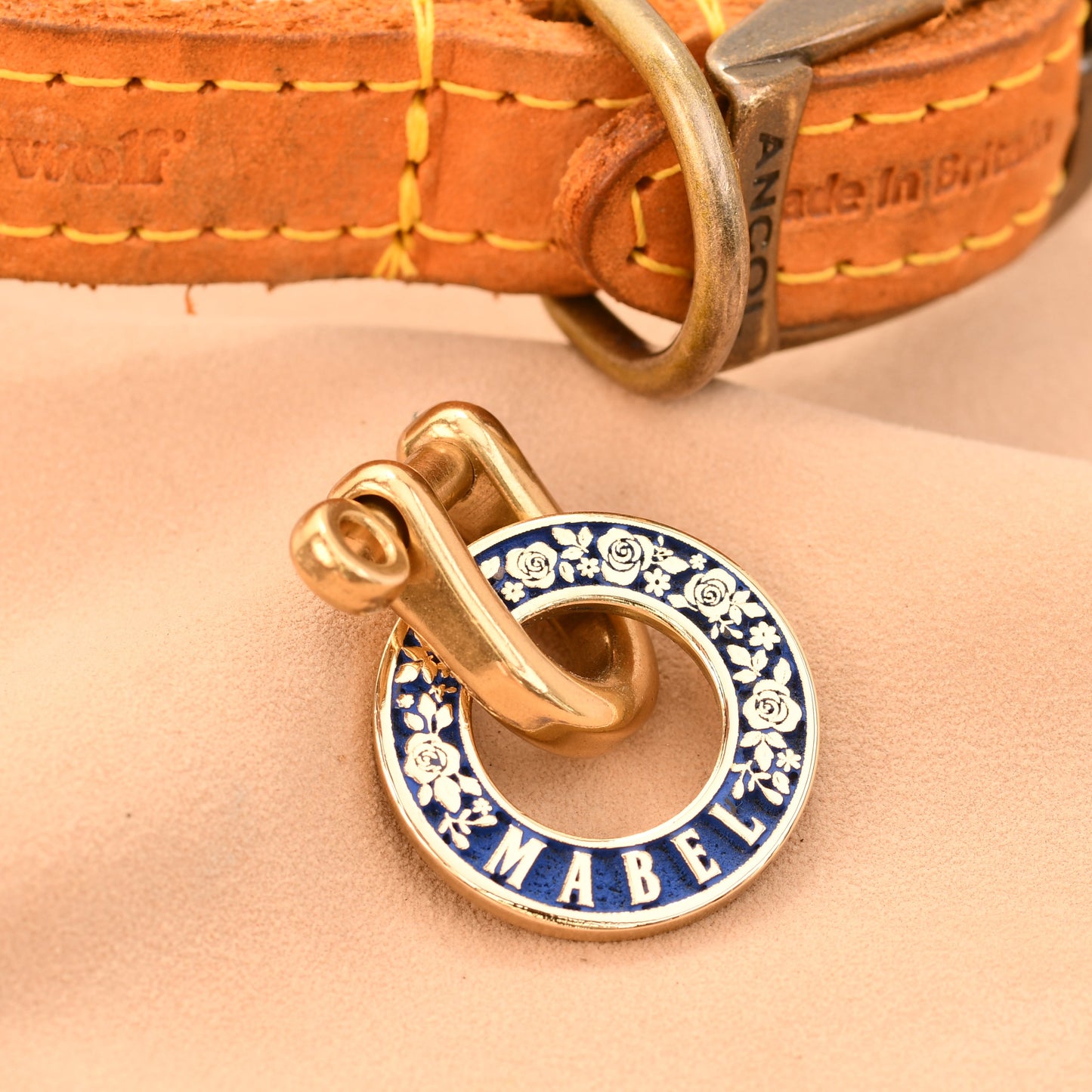 Dog collar with a gold and blue 'Made' tag on a beige background