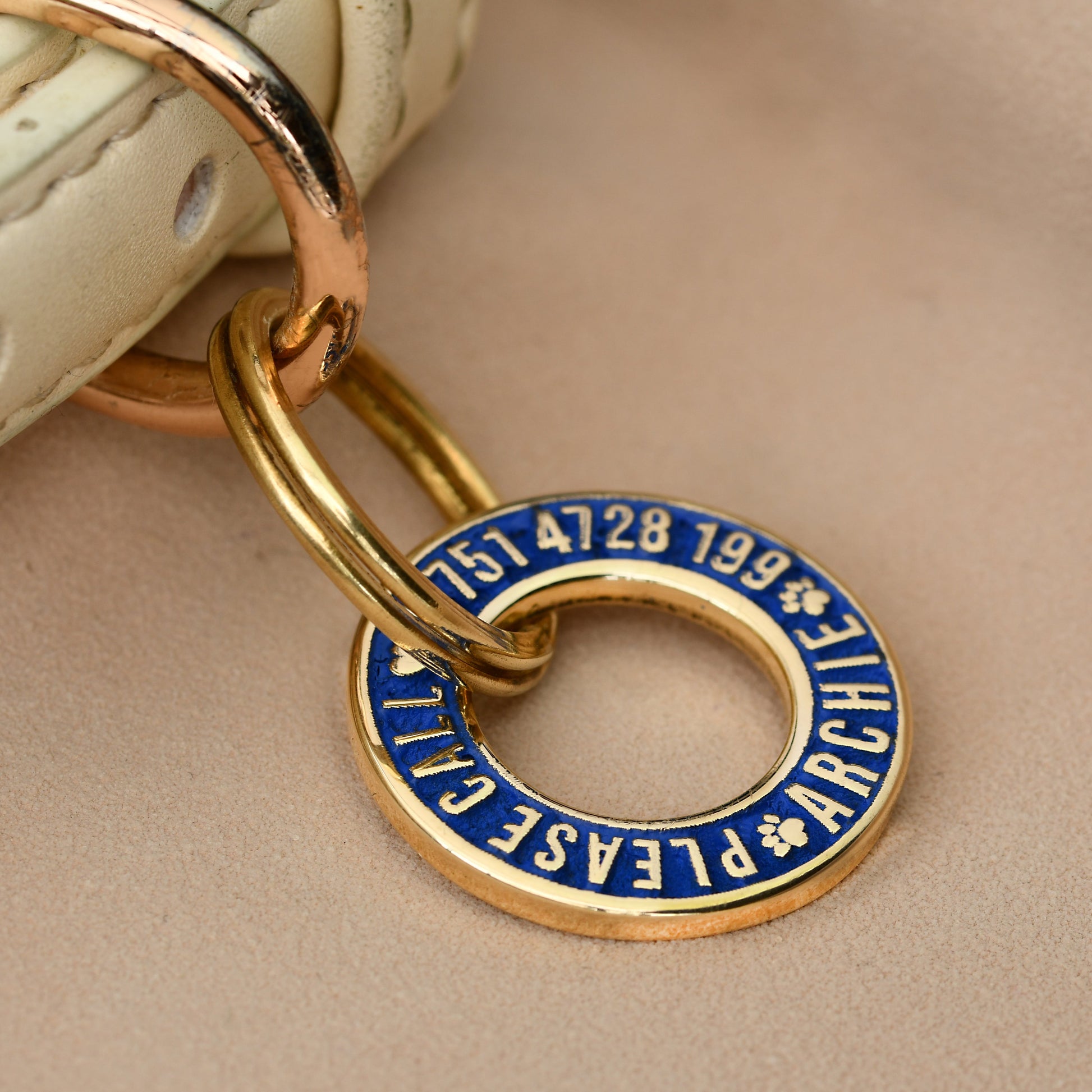 Hoop-shaped brass ID tag with deep custom engraving, handmade in the UK. Suitable for dogs, cats, and horse bridles, shown attached to a collar for display.