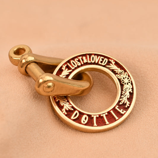 Gold dog tag with 'Lost & Loved' engraving on a beige background