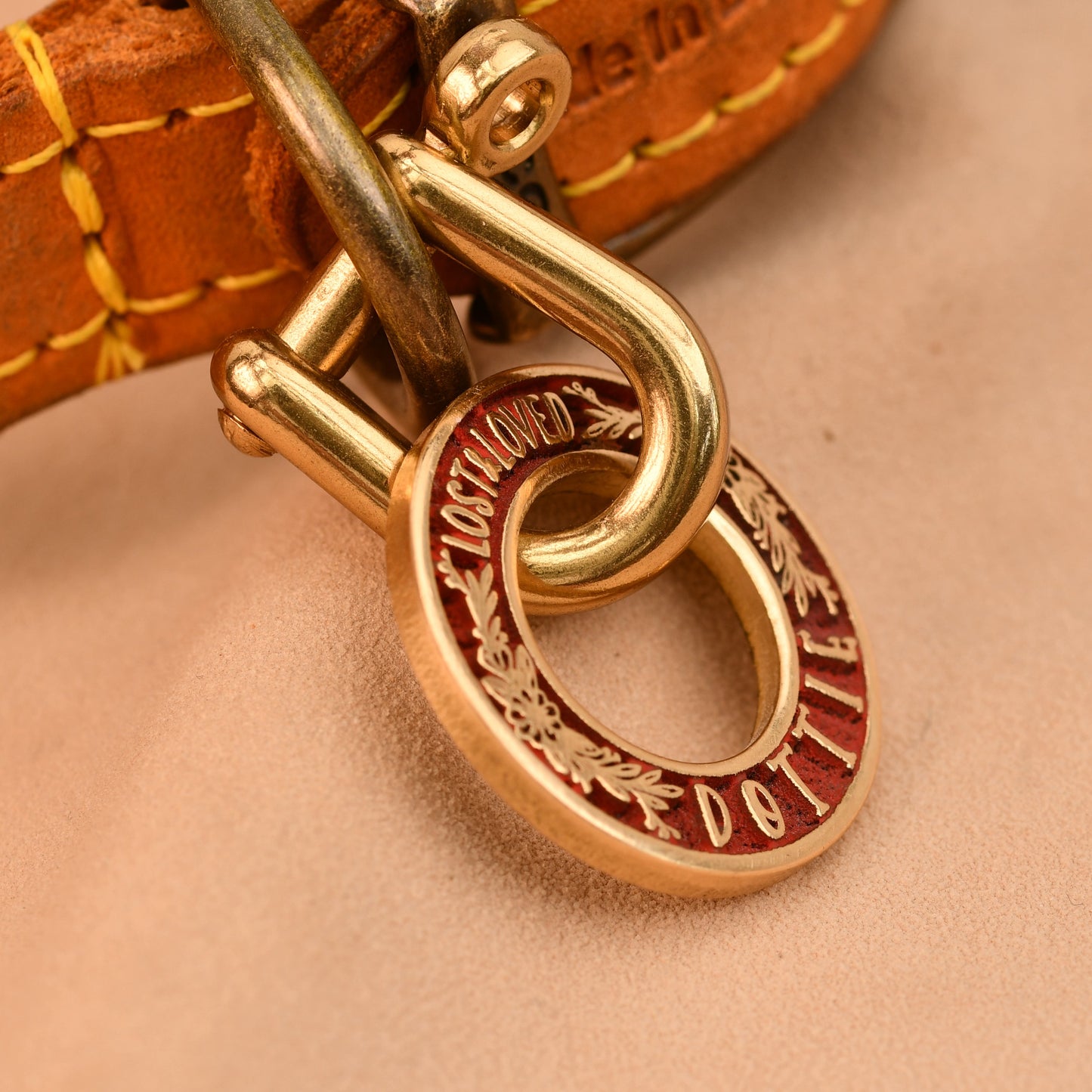 Close-up of a gold dog collar with a brand logo on a beige background