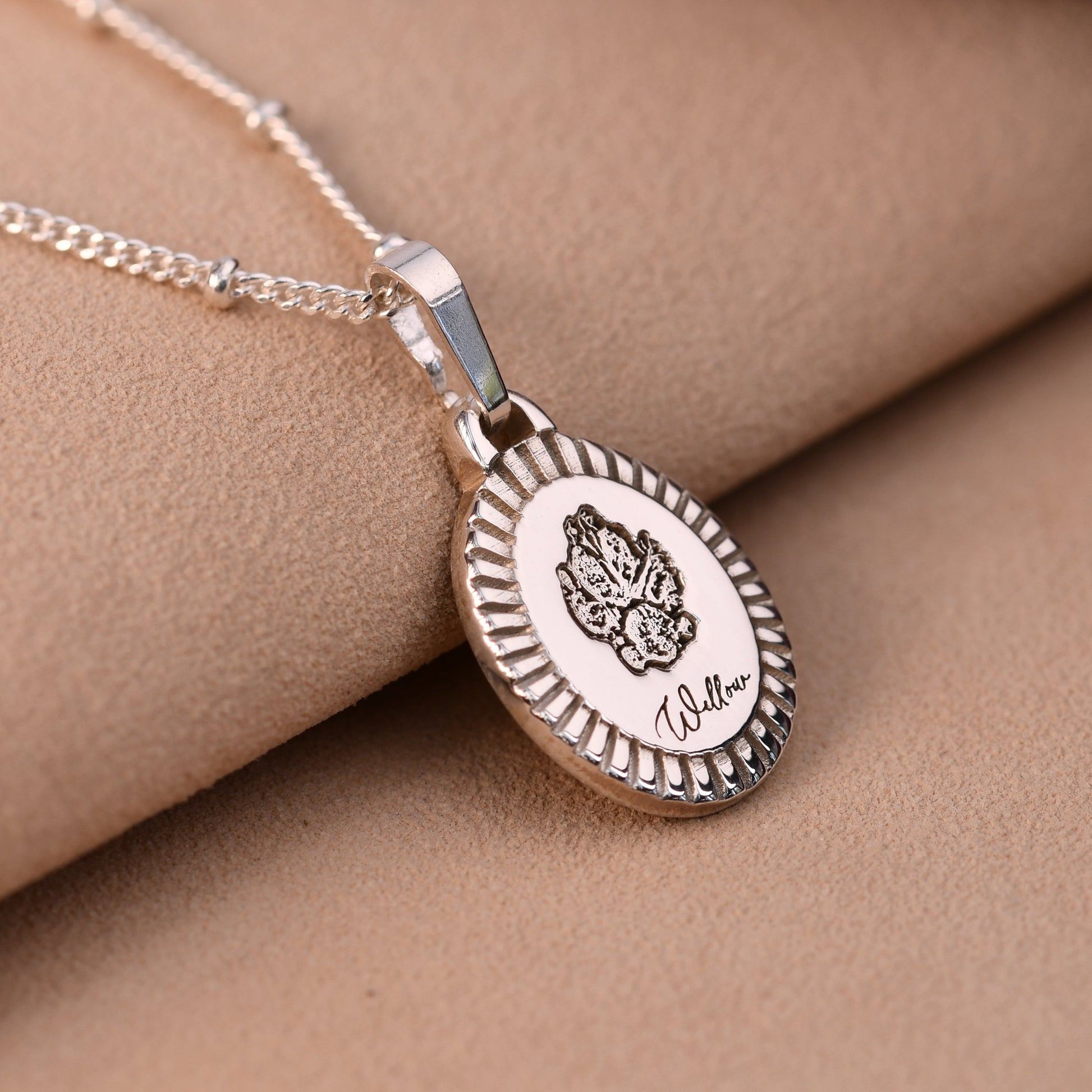 Silver necklace with a pendant on a beige fabric background