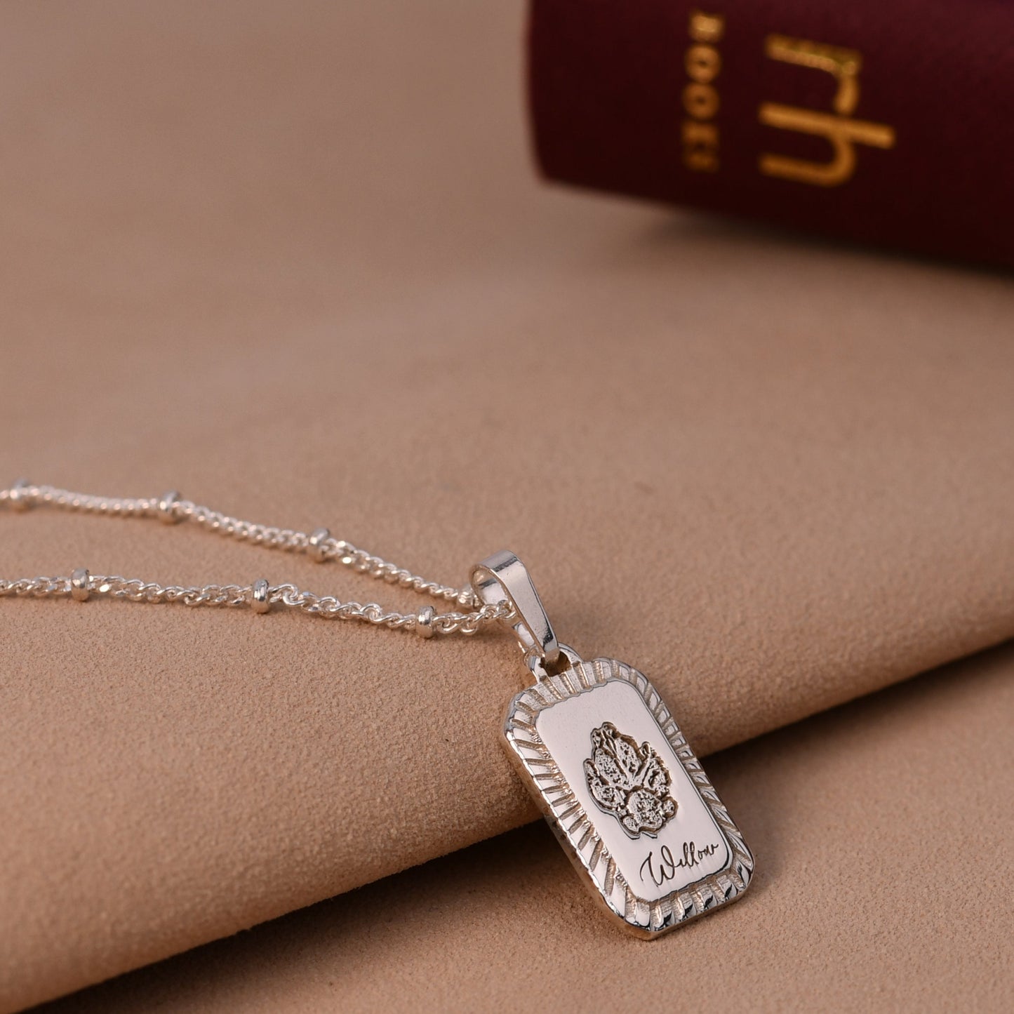 Silver necklace with a pendant on a beige fabric background