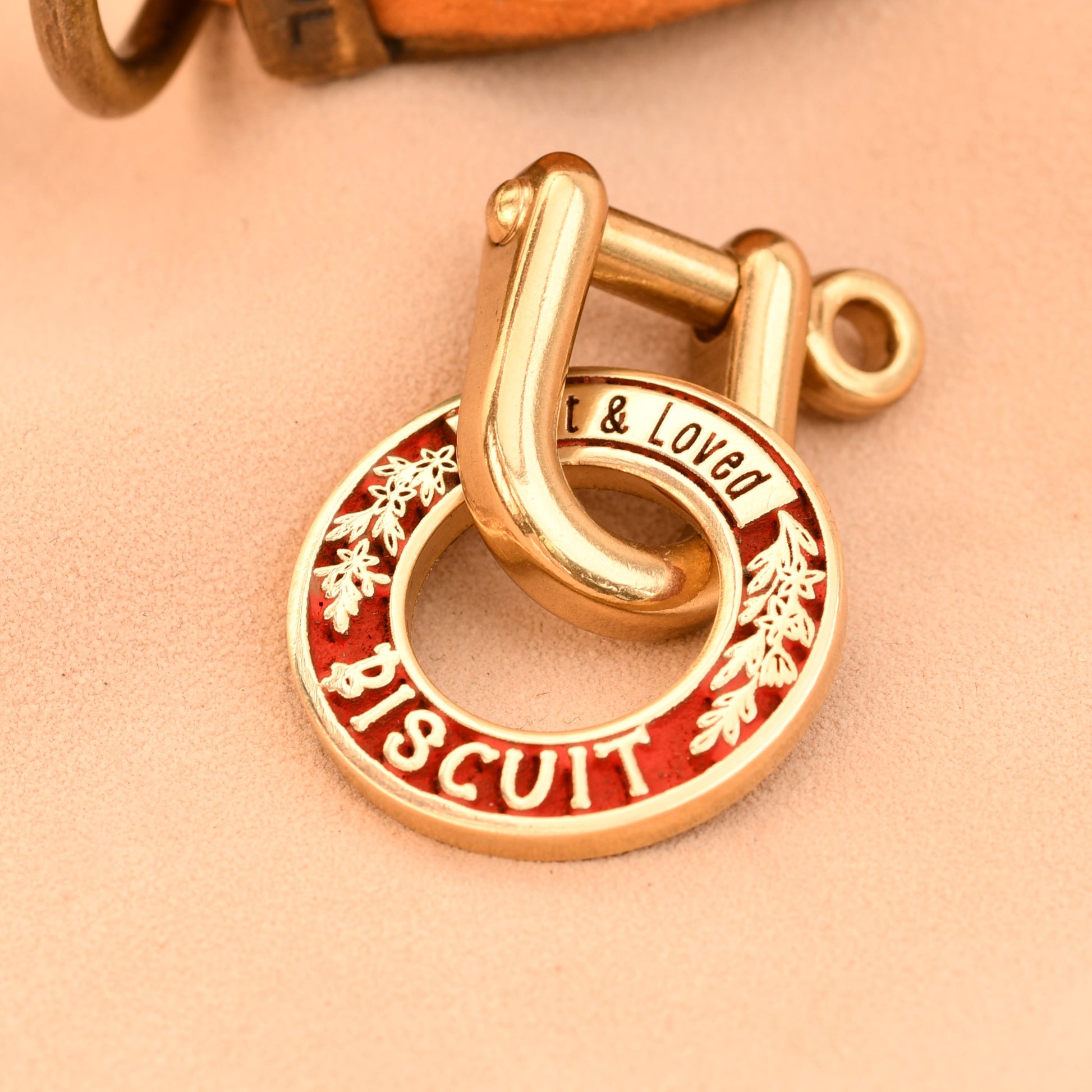 Gold charm with red enamel on a beige background