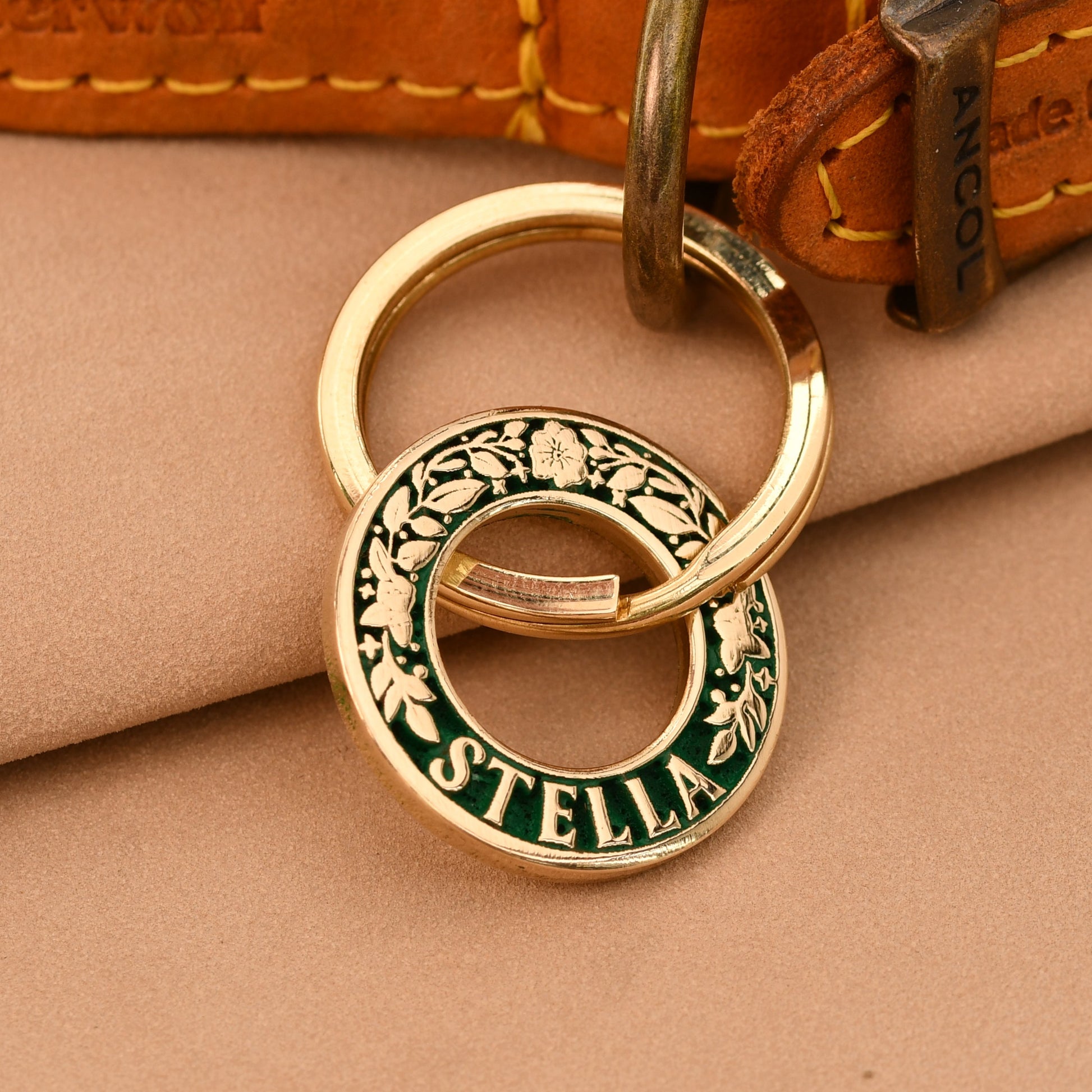Gold keychain with 'Stella' on a brown leather surface