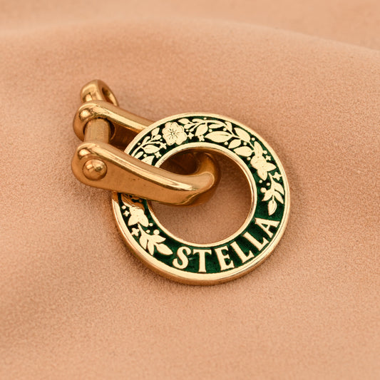 Gold and green 'Stella' charm on a beige background