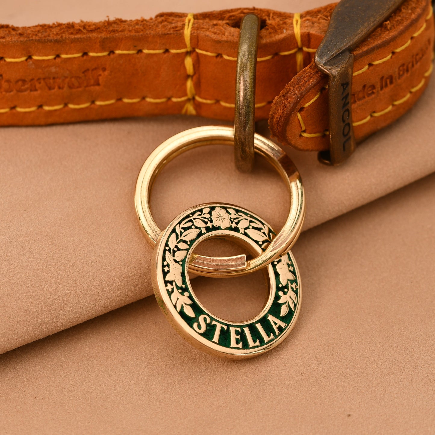 Gold dog collar with a engraved tag on a beige fabric background