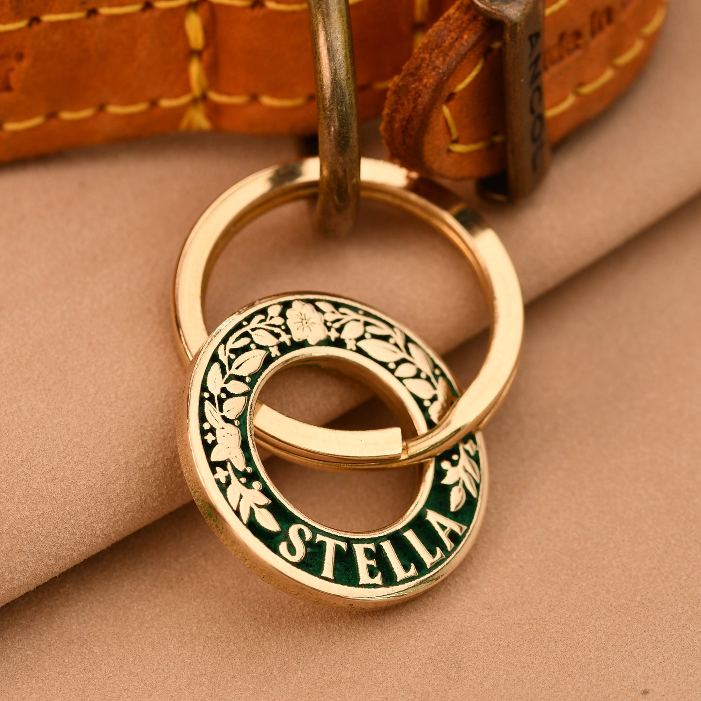 Gold keychain with 'Stella' engraving on a beige surface