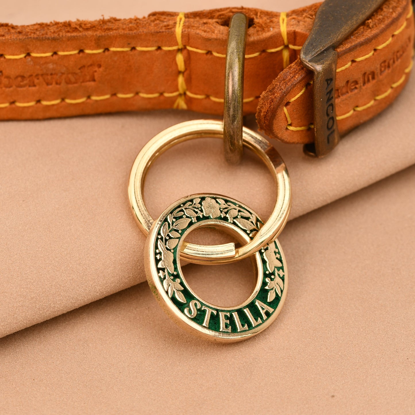 Gold and green dog tag on a leather collar with Timberland branding.