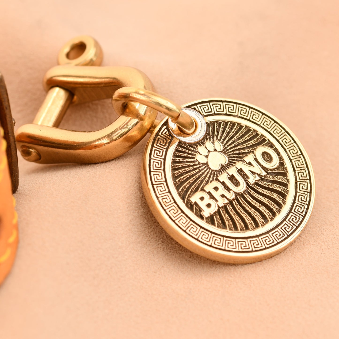 Gold dog tag with 'BRUNO' engraved on a beige background