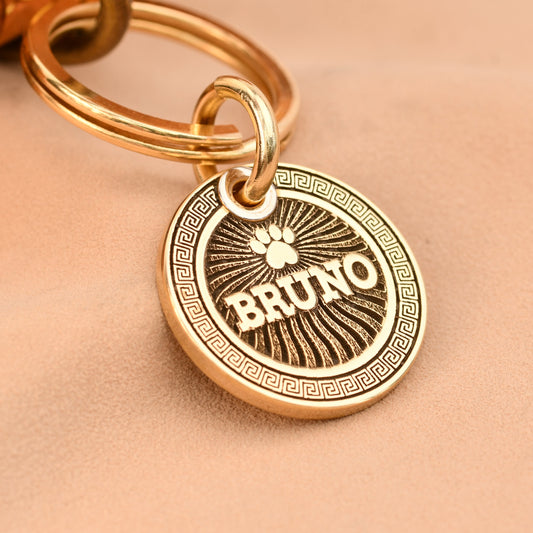 Gold keychain with 'BRUNO' pendant on a beige background