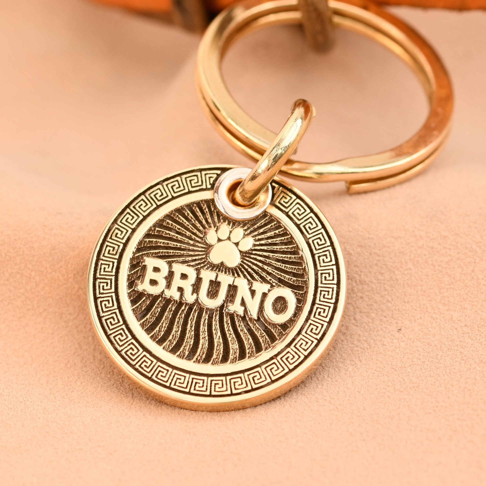 Gold keychain with a circular tag featuring the name 'Bruno' on a beige background