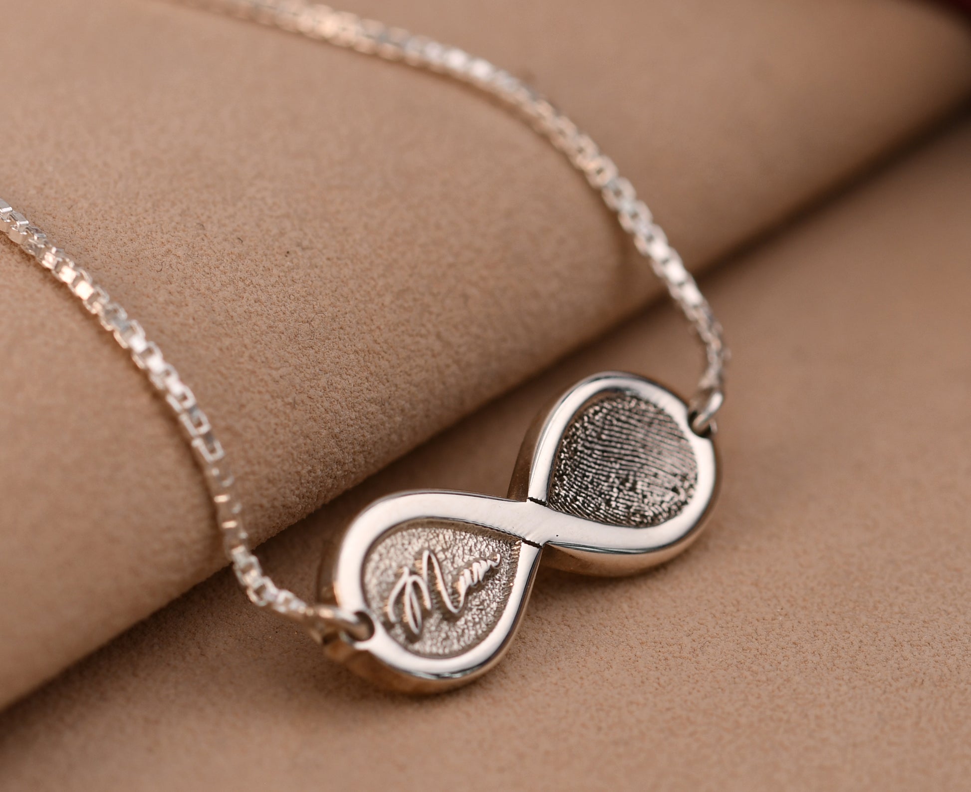Silver necklace with interlocking heart pendants on a brown surface