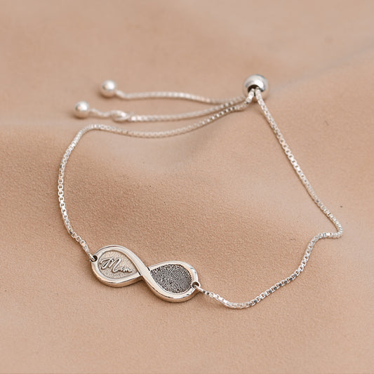Silver bracelet with an infinity symbol on a beige surface