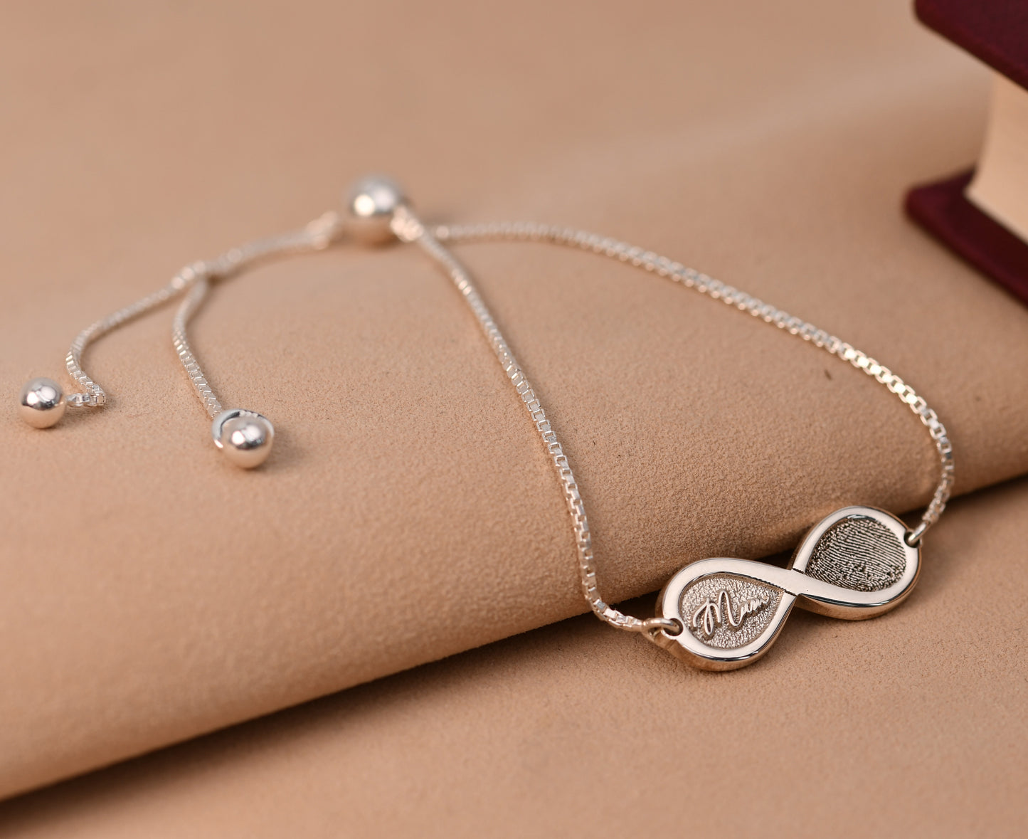 Infinity fingerprint bracelet in sterling silver, engraved with a fingerprint and the name Mum, on an adjustable box chain

