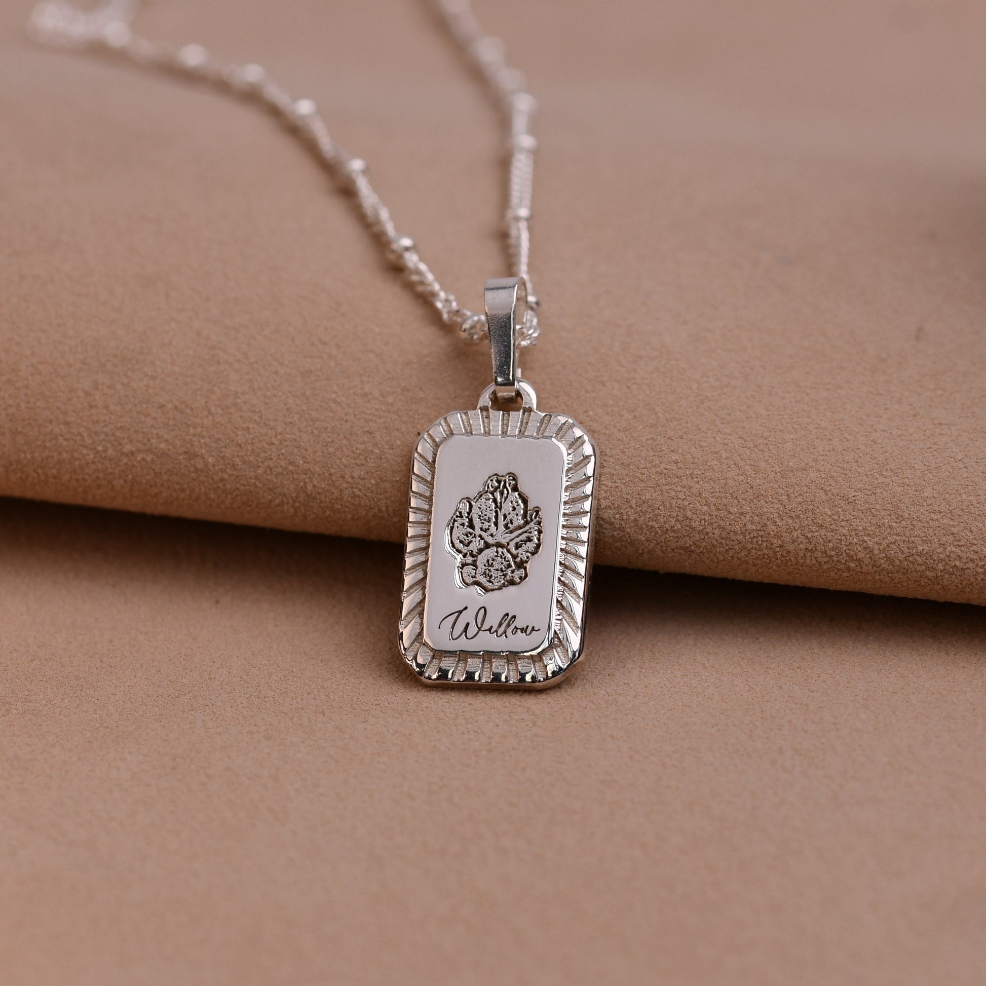 Silver necklace with a pendant on a beige surface