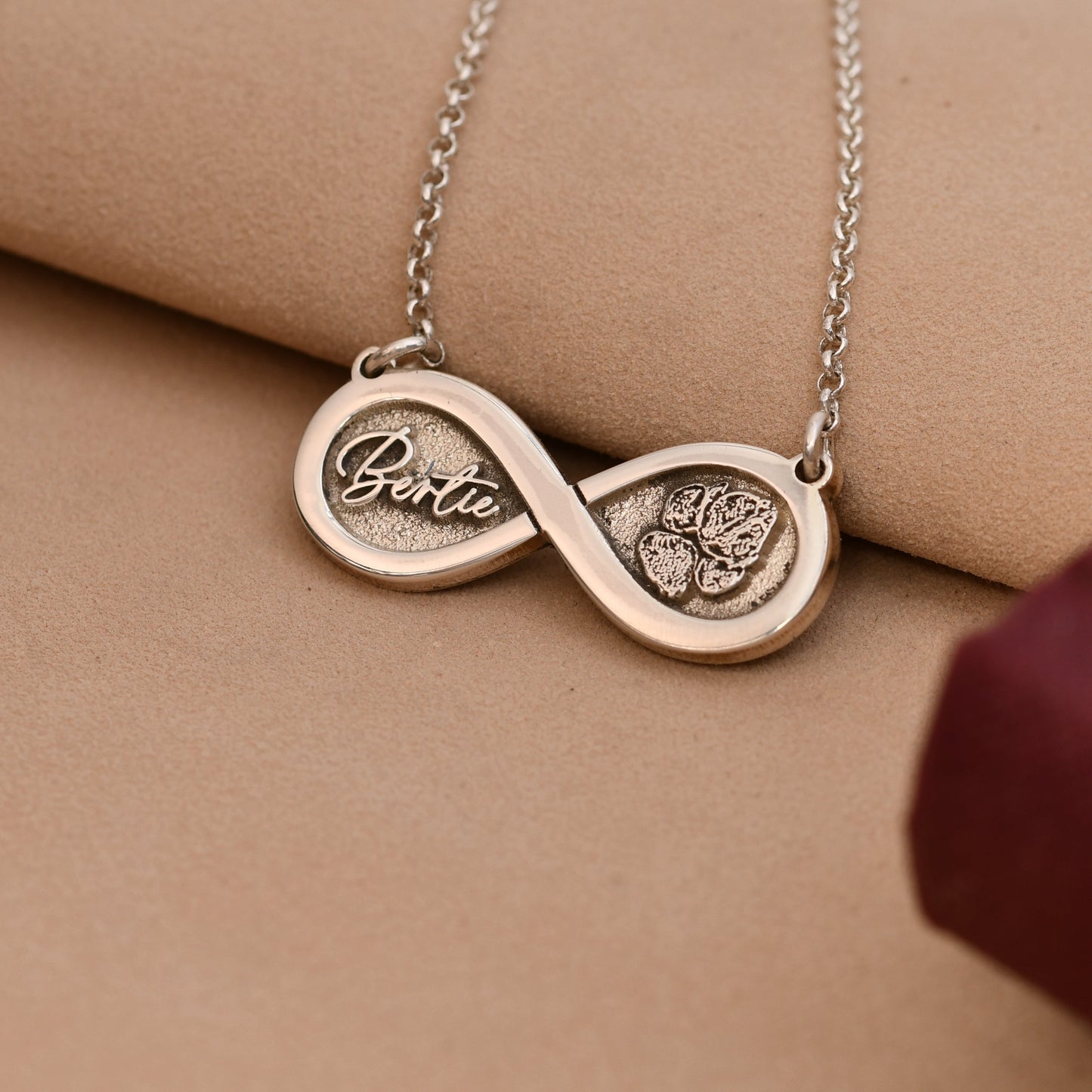 Silver necklace with an infinity symbol pendant on a beige surface