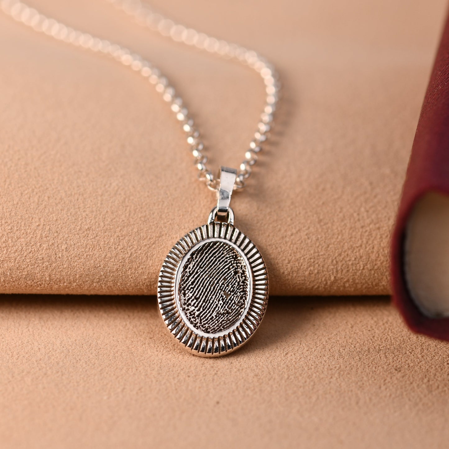 Oval fingerprint necklace in sterling silver with a finely rayed border, engraved with a fingerprint