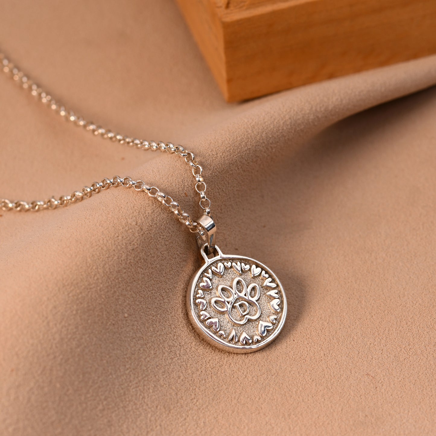 Silver necklace with a detailed pendant on a beige fabric background