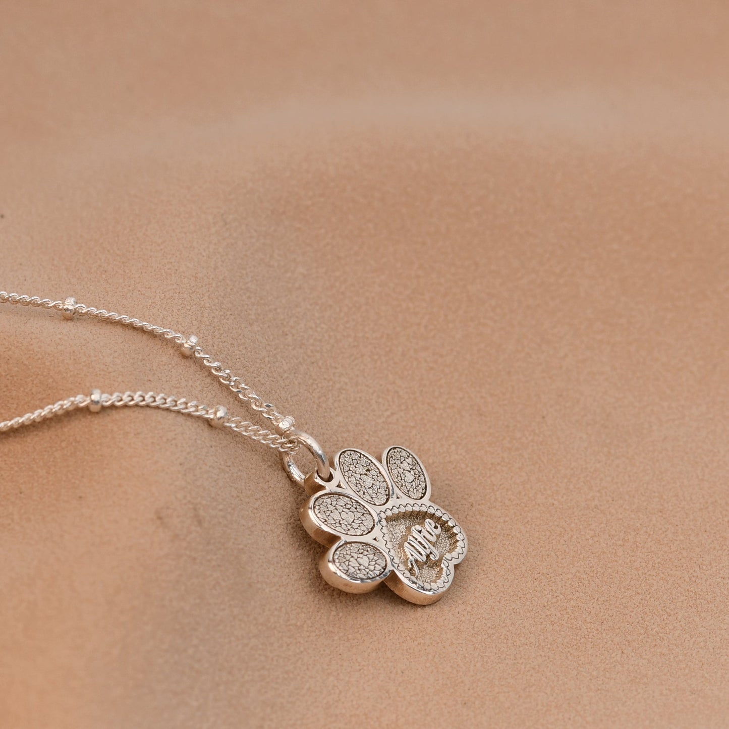 Silver necklace with a clover-shaped pendant on a blurred background