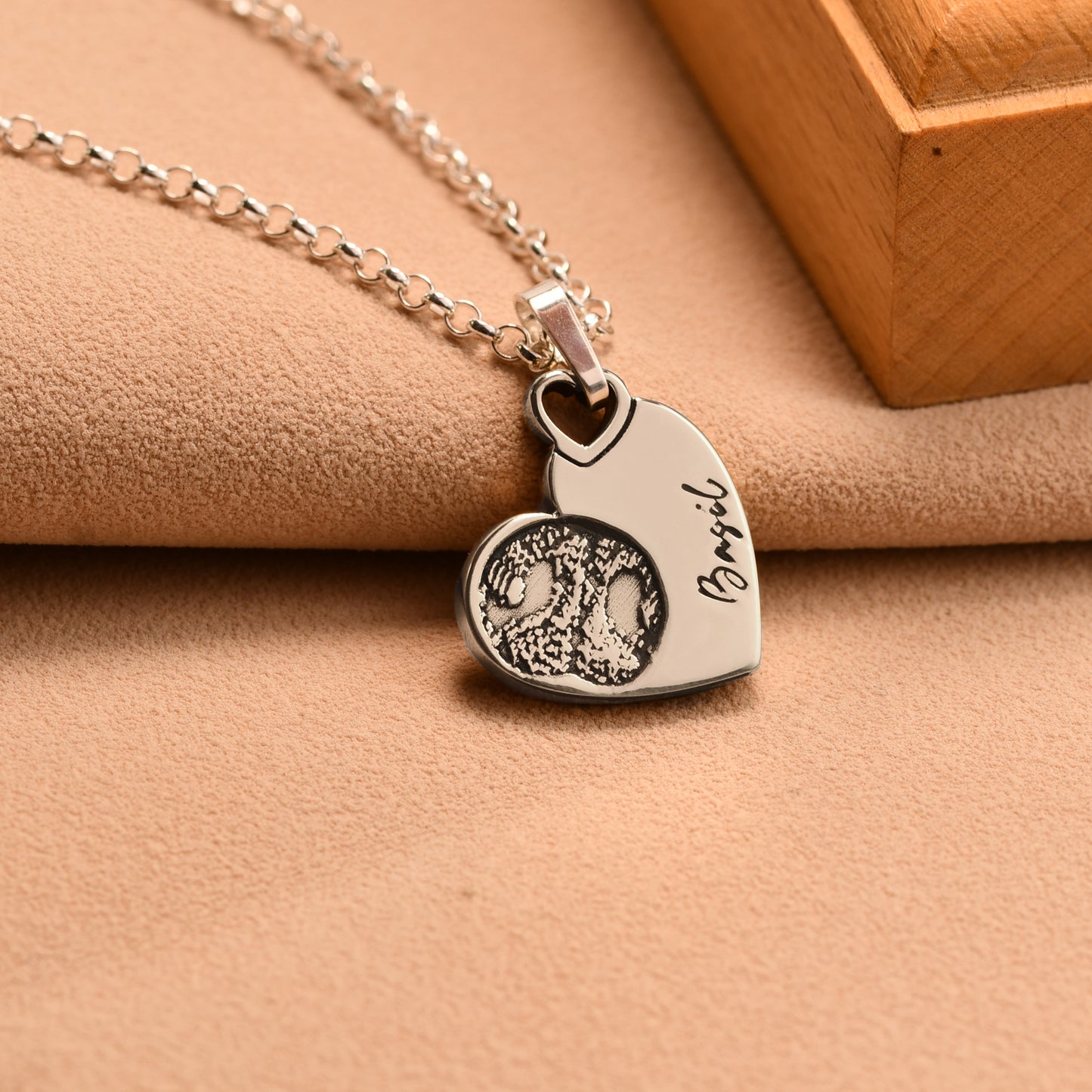 Silver necklace with a heart-shaped pendant on a beige surface
