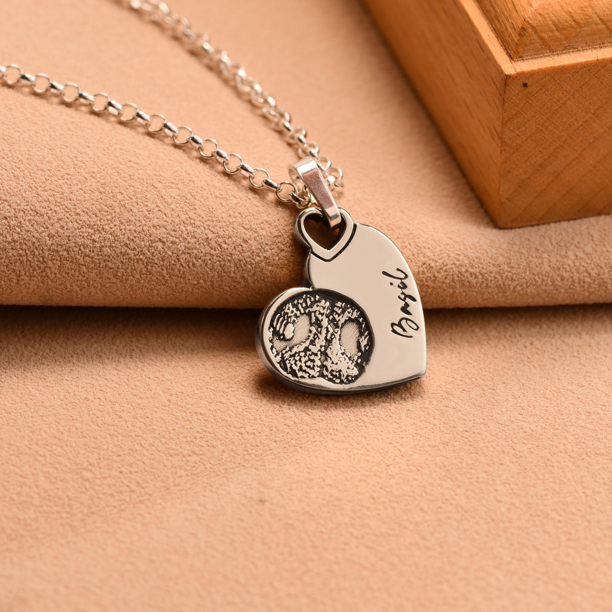 Silver necklace with a heart-shaped pendant on a beige surface