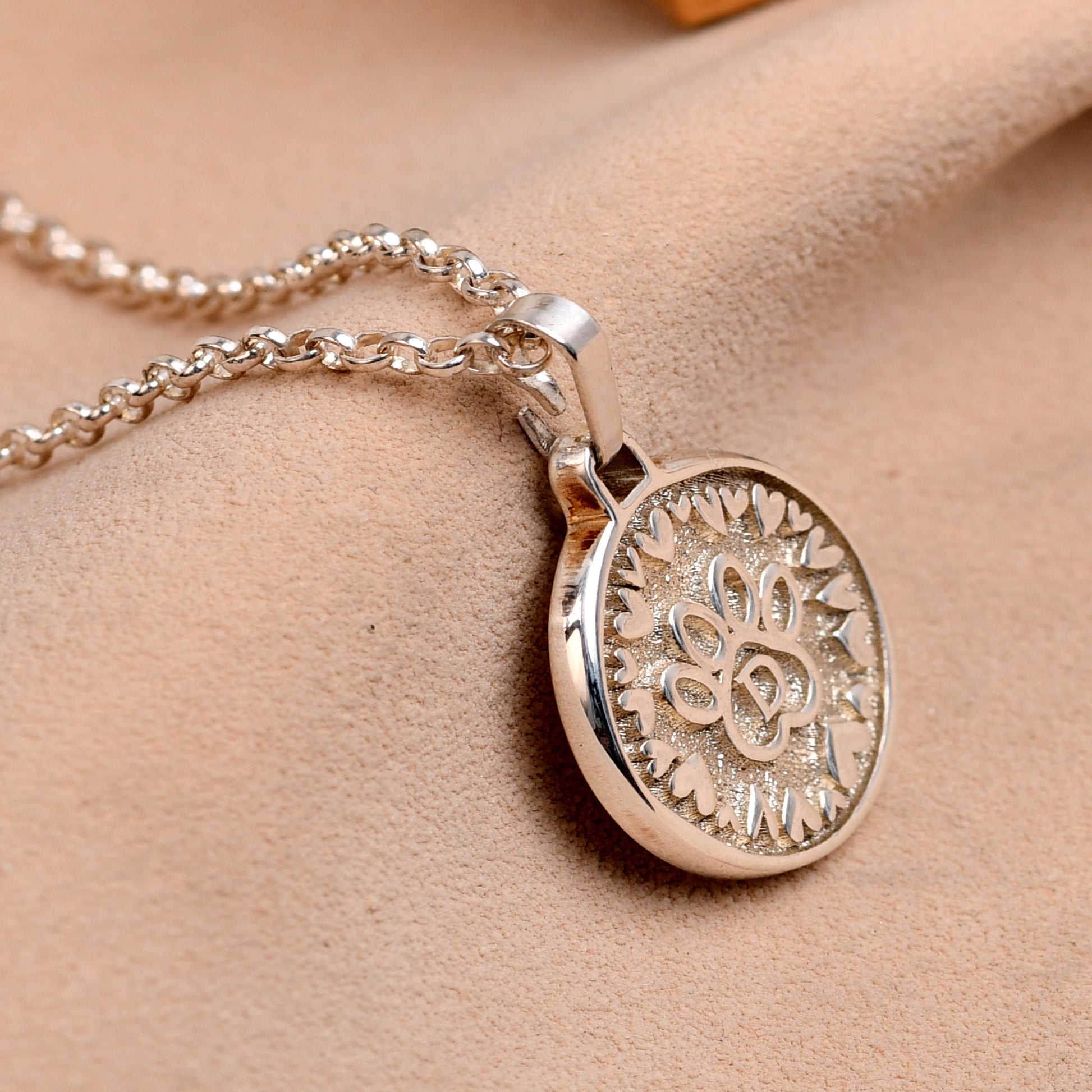 Silver necklace with a detailed pendant on a beige background