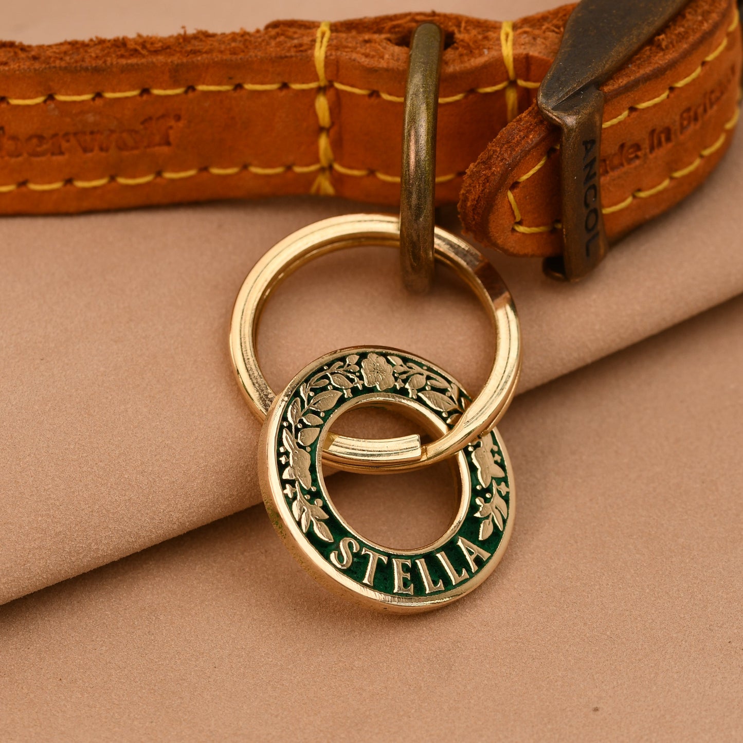 Dog collar with a gold tag on a beige fabric background