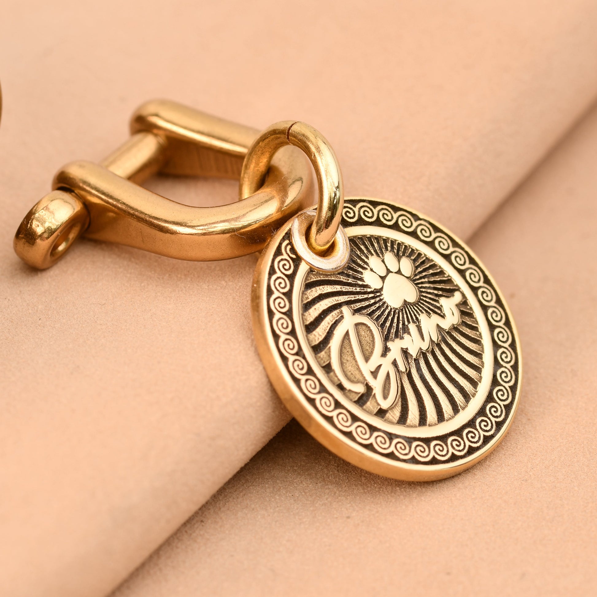 Gold dog tag with engraved design on a beige background