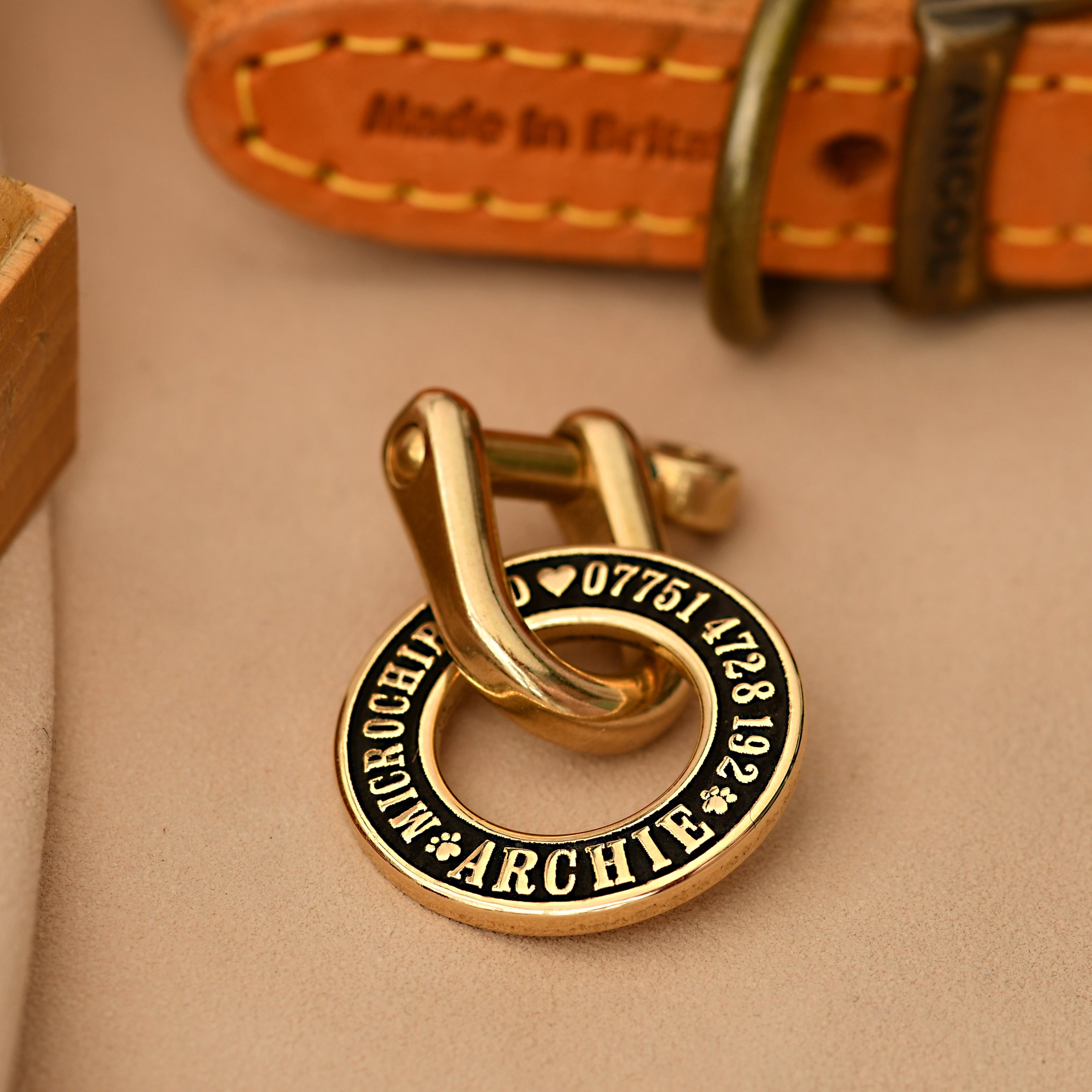 Hoop-shaped brass ID tag with deep custom engraving, handmade in the UK. Suitable for dogs, cats, and horse bridles, shown attached to a collar for display.
