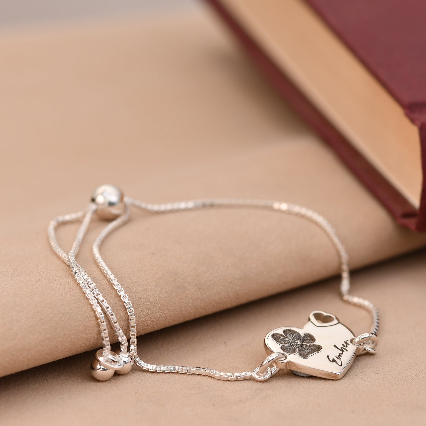 Silver bracelet with a heart-shaped charm on a beige surface