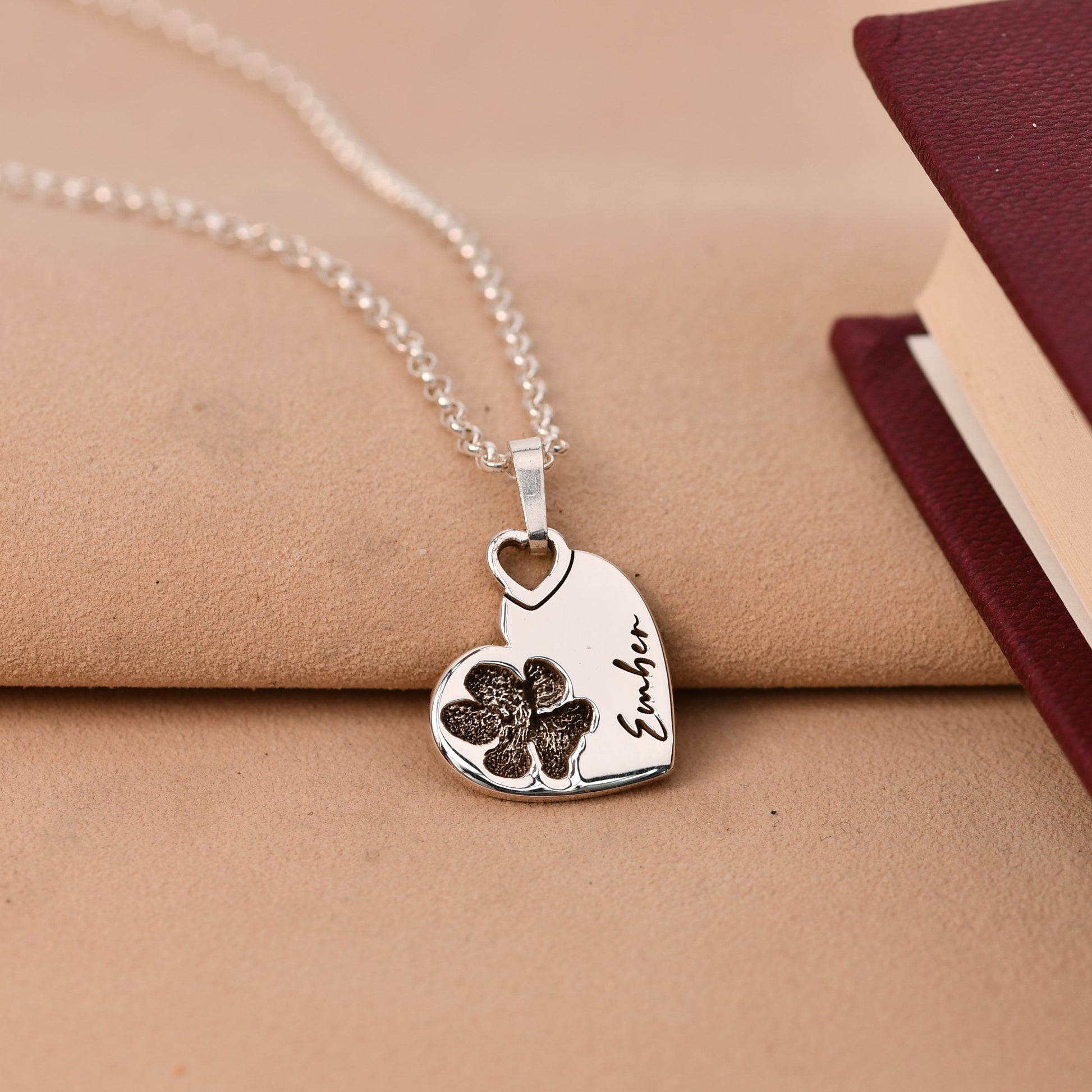 Silver heart-shaped necklace with a pendant on a beige surface