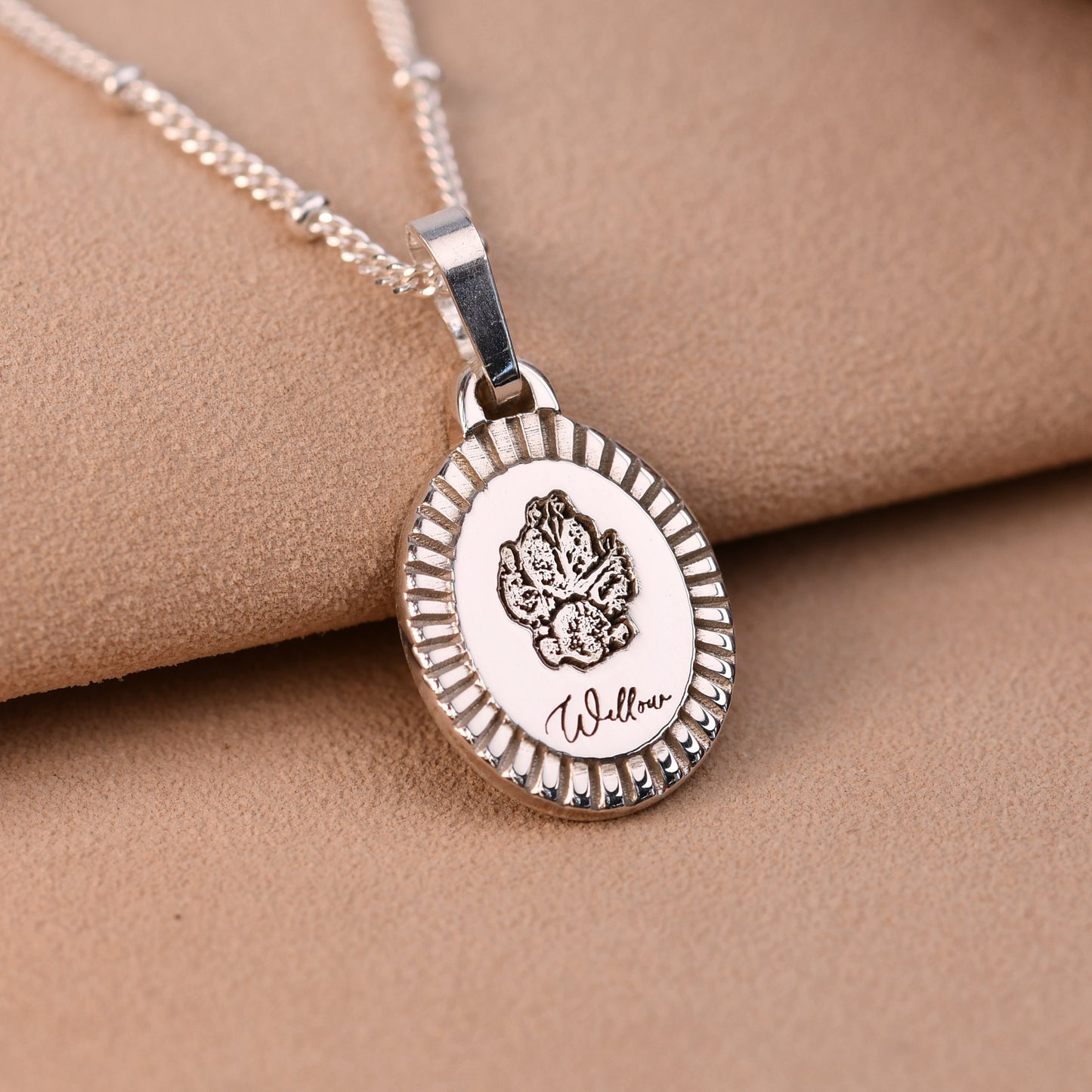 Silver necklace with a round pendant on a beige fabric background
