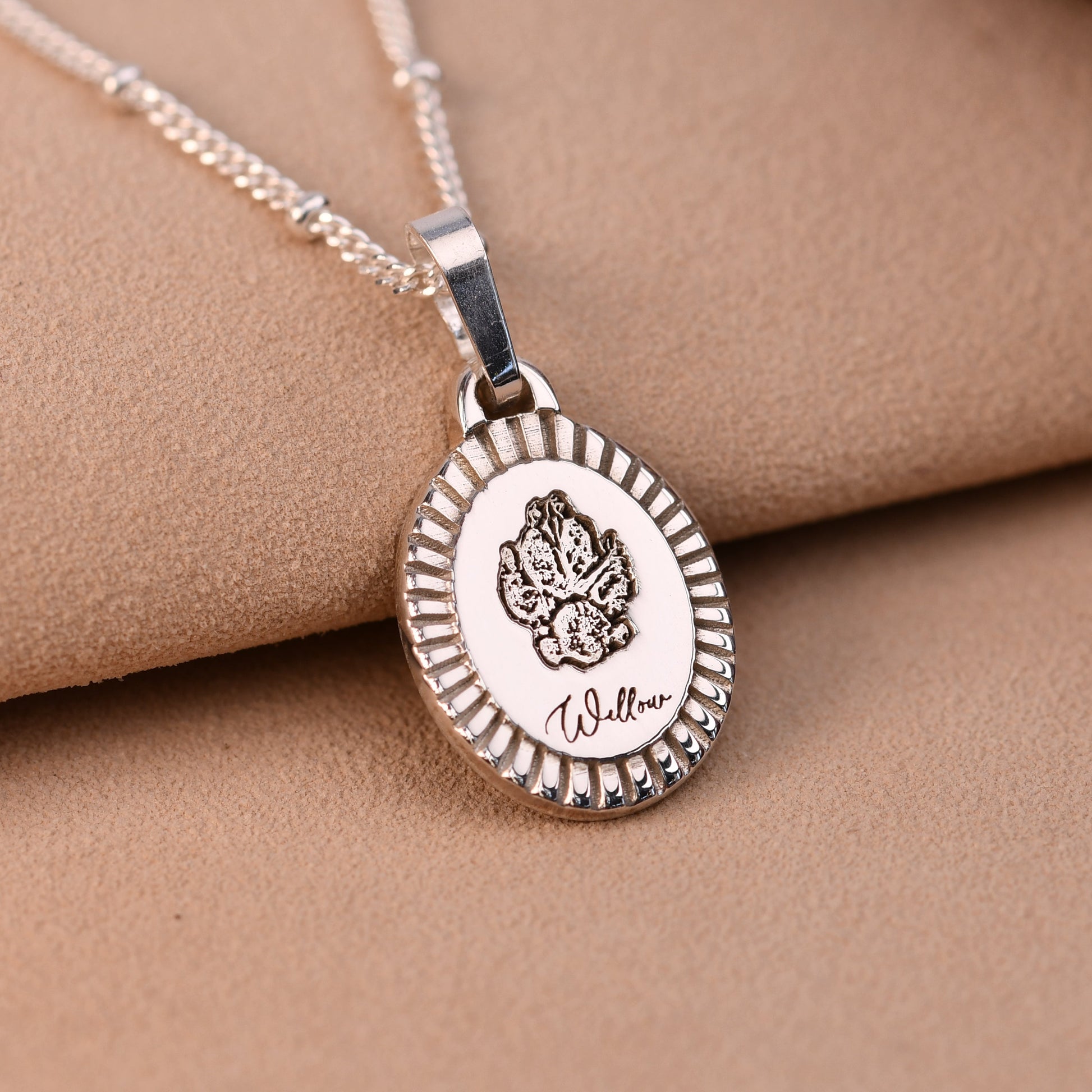 Silver necklace with a round pendant on a beige fabric background